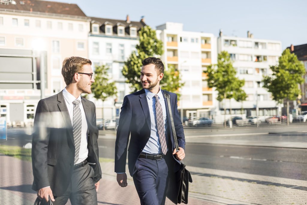 Two young businessmen walking in city